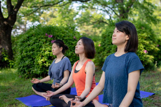 istock Women practicing yoga in public park 957987556