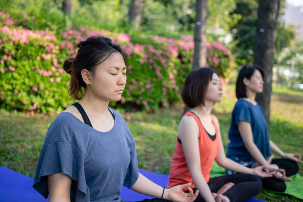 istock Three women practicing yoga in public park 957987578