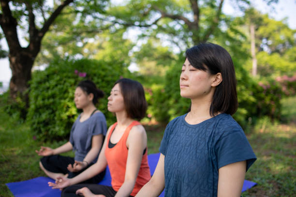 istock Three women practicing yoga in public park 957987580