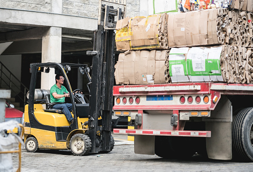 Man working in a recycling center sorting the garbage using a forklift - environmental concepts