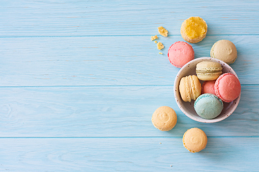 Assortment of colorful homemade  macarons on blue wood background. Top view. Copy space