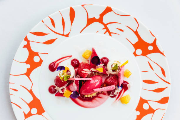 istock Modern French sweets: Strawberry mouse with merengue, rose, crumble & vanilla milk shake on white plate with red colour pattern. 957994412