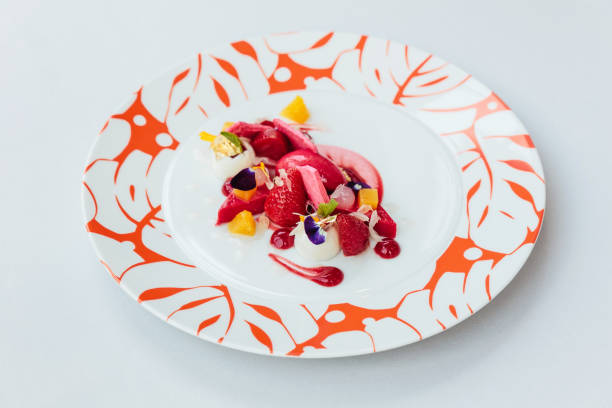 istock Modern French sweets: Strawberry mouse with merengue, rose, crumble & vanilla milk shake on white plate with red colour pattern. 957994500
