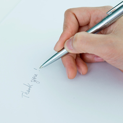 Woman writing thank you on paper.