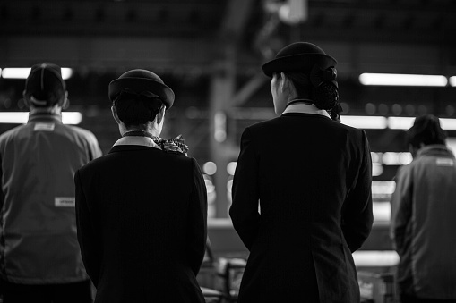 A group of train attendants and staff waiting for the bullet train in uniformity. 

Osaka, Japan : December 17, 2014