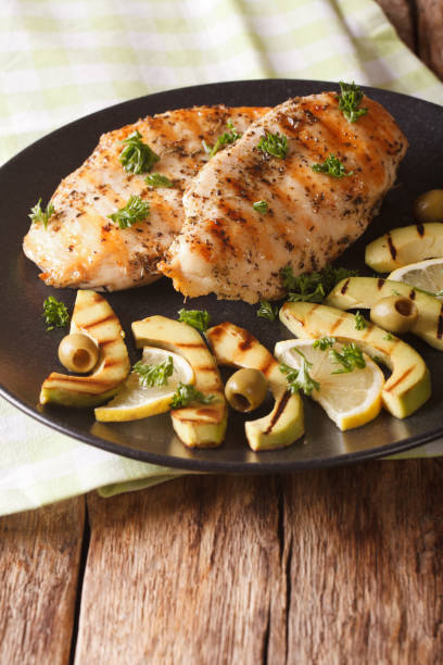 istock Chicken fillet with grilled avocado, lemon and olive close-up. vertical 958003346