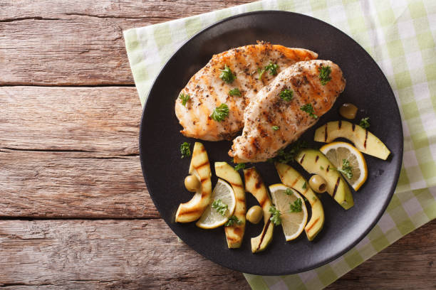 Grilled chicken breast with avocado, lemon and olive close-up. horizontal top view