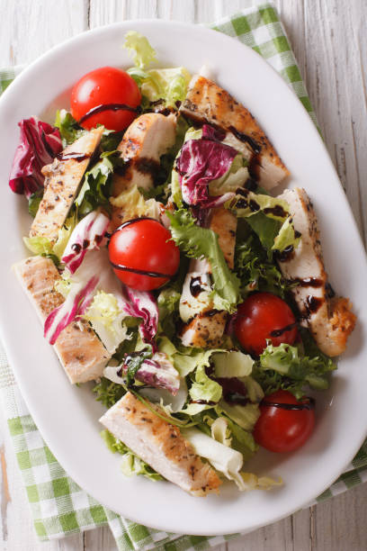 istock Fresh chicken salad, tomatoes and herbs with balsamic sauce close-up. Vertical top view 958005198