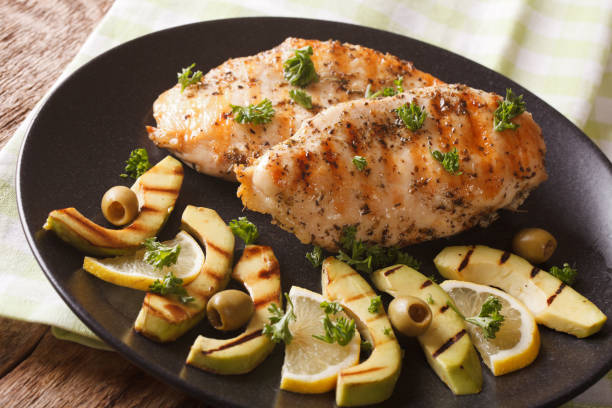 istock Chicken fillet with grilled avocado, lemon and olive close-up. Horizontal 958005232