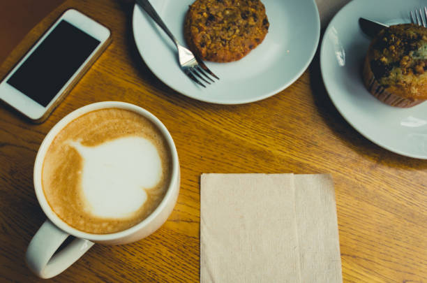 istock love coffee in white cup with chocolate cupcake and smartphone on wood table. 958016394