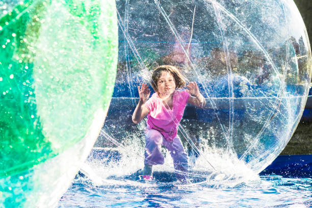 Girl in Zorbing Ball Young girl playing inside a floating water walking ball. zorb ball stock pictures, royalty-free photos & images