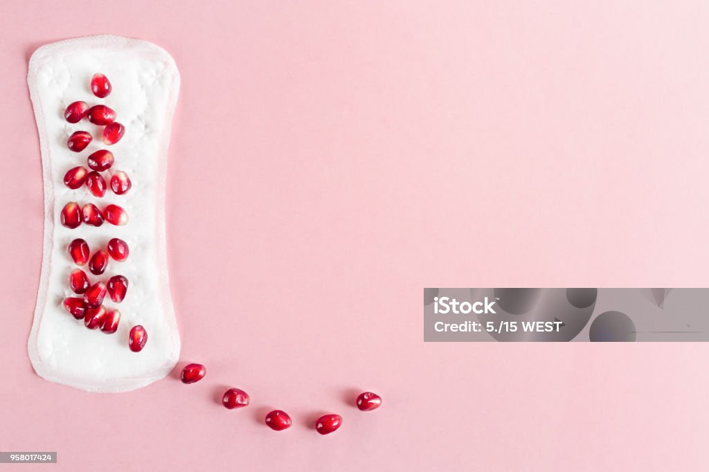 Menstrual pad with pomegranate on a pink background. Top view. Copy space Blood Stock Photo