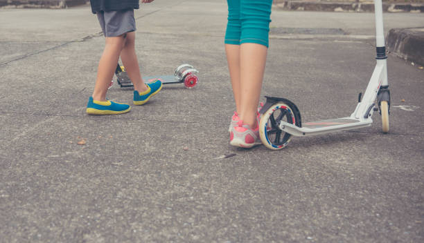 istock Asian boy and girl playing scooter field. 958021966
