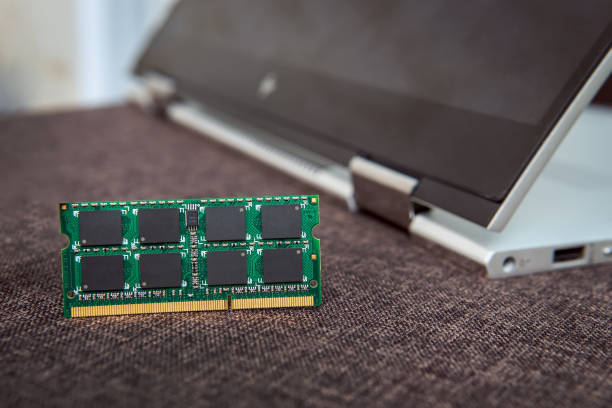 Memory card RAM for laptop on the background of a laptop-transformer folded into a tablet. DDR for modern gadgets. Computer repair. Increase the amount of memory for the computer.