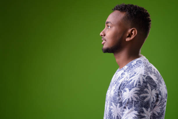 istock Young handsome African man against green background 958030404