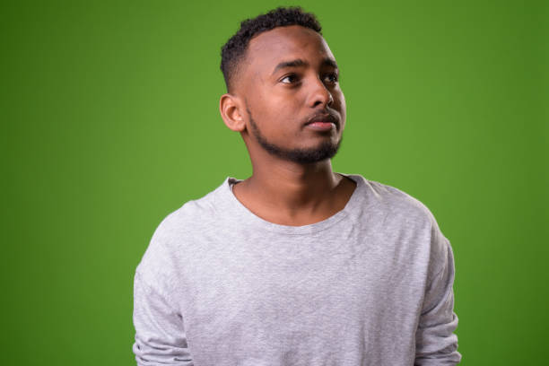 istock Young handsome African man against green background 958031012
