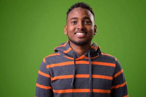 istock Young handsome African man against green background 958031424