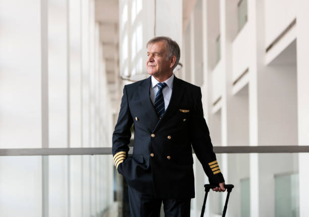 istock Experienced Senior pilot pulling his luggage in the airport terminal 958033994