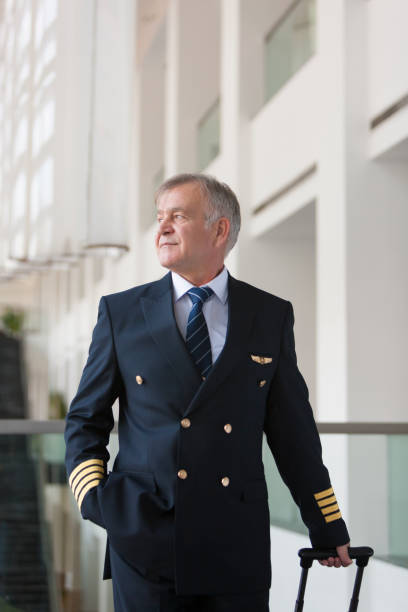 istock Experienced Senior pilot pulling his luggage in the airport terminal 958034034