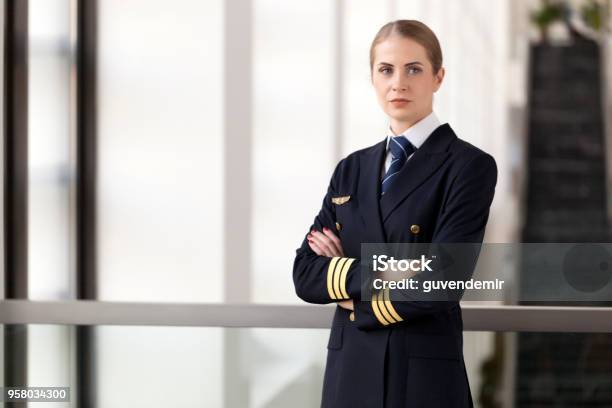 Portrait Of Female Pilot Standing At Airport Lobby Stock Photo - Download Image Now - Pilot, Women, One Woman Only