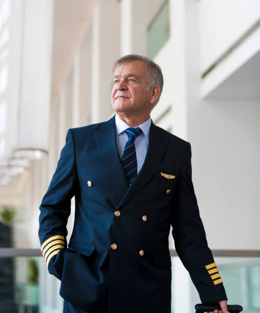 istock Experienced Senior pilot pulling his luggage in the airport terminal 958037970