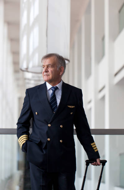 istock Experienced Senior pilot pulling his luggage in the airport terminal 958038594