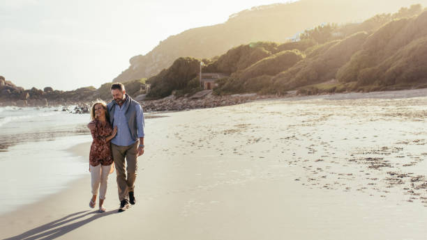 istock Senior couple strolling on the beach 958044326