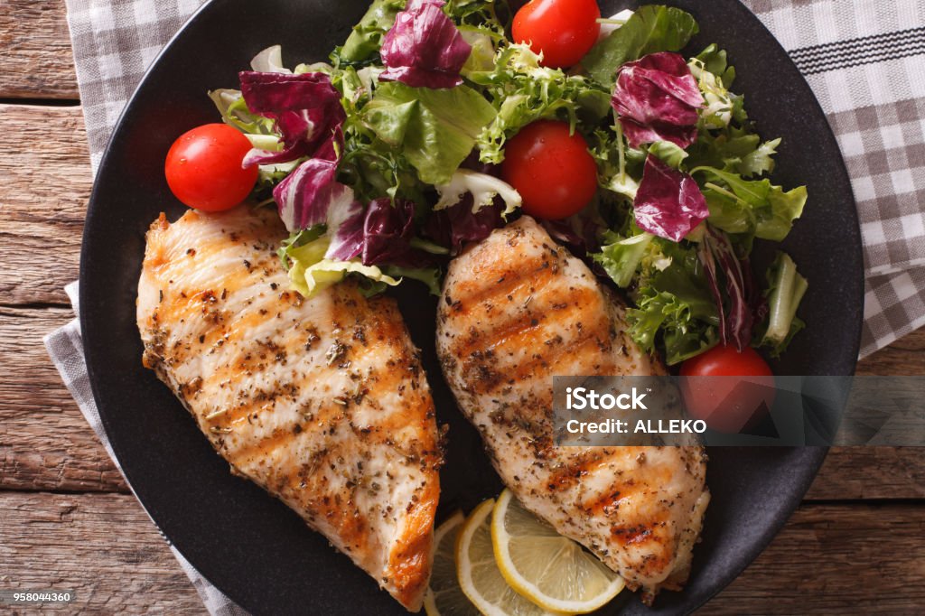 Grilled chicken breast with mixed salad close-up. horizontal top view Grilled chicken breast with mixed salad on a plate close-up. horizontal view from above Chicken Breast Stock Photo