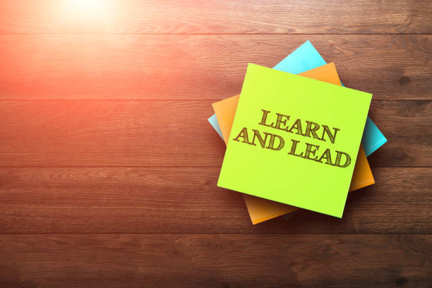 istock Learn and Lead, the phrase is written on multi-colored stickers, on a brown wooden background. Business concept, strategy, plan, planning. 958046192