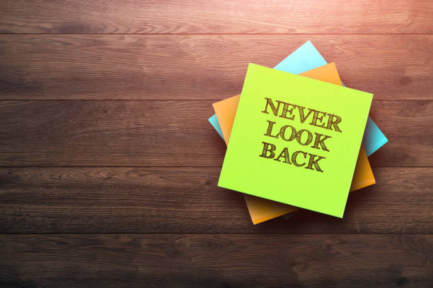 istock Never Look Back, the phrase is written on multi-colored stickers, on a brown wooden background. Business concept, strategy, plan, planning. 958046338