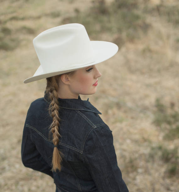 istock Cowgirl in jeans jacket standing in field. Side view. 958050892