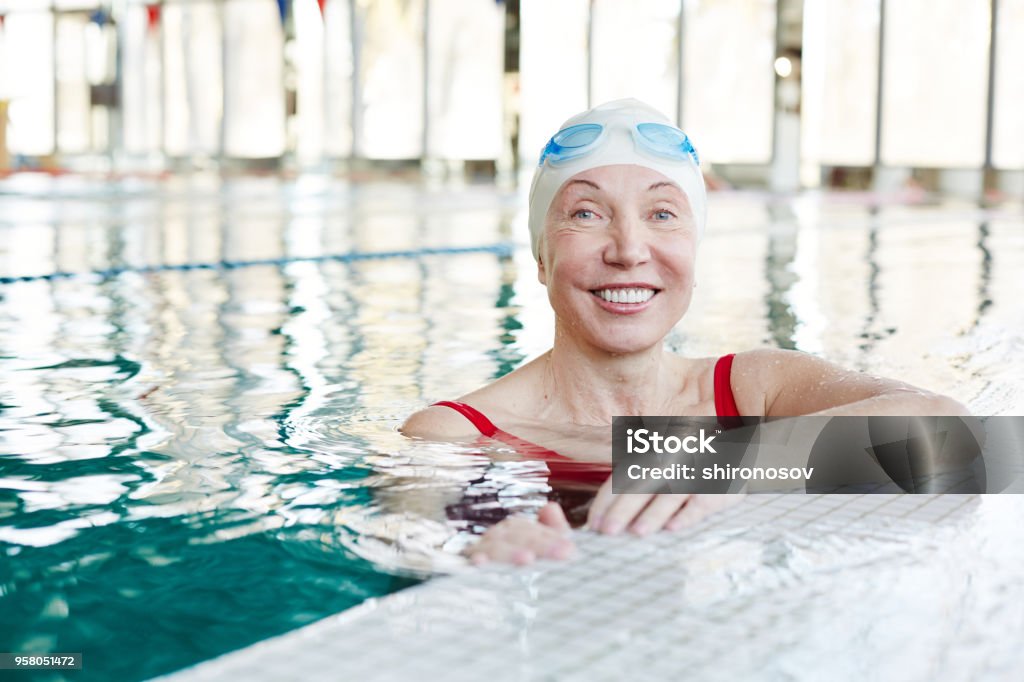 Healthy lifestyle Happy and healthy senior female with toothy smile looking at you while spending leisure in swimming-pool Swimming Stock Photo