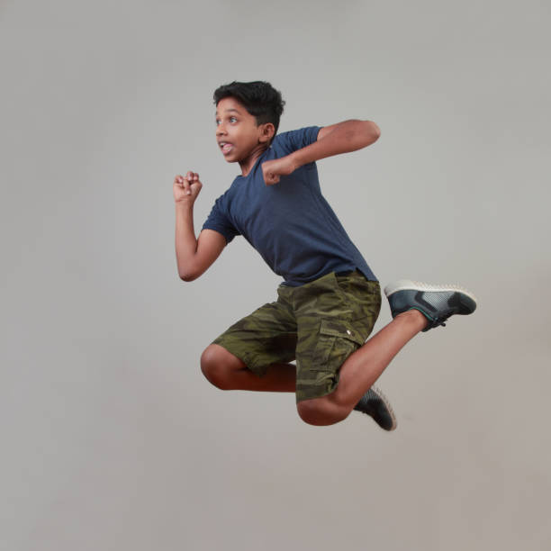 istock Excited young boy jumps against a wall background 958054038