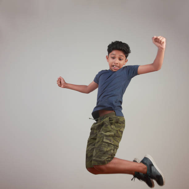 istock Excited young boy jumps against a wall background 958054040