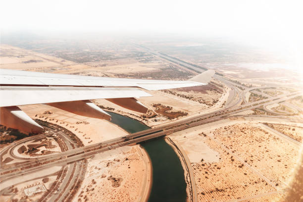 luftbild aus flugzeugfenster unten auf straßen mit autos in der wüste bei sonnenuntergang - fog desert arabia sunset stock-fotos und bilder