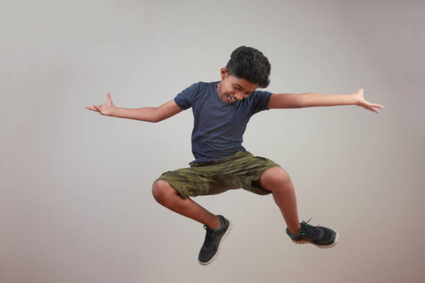 istock Excited young boy jumps against a wall background 958054858