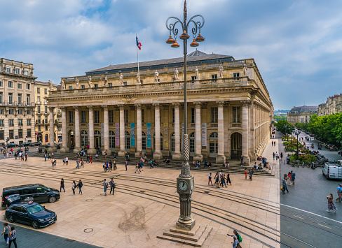 Bordeaux, France, 8 may 2018 - Tourist and locals walking on the Main square 'Place de La Comedie' passing the grand Opera House 'Grand Theatre de Bordeaux'
