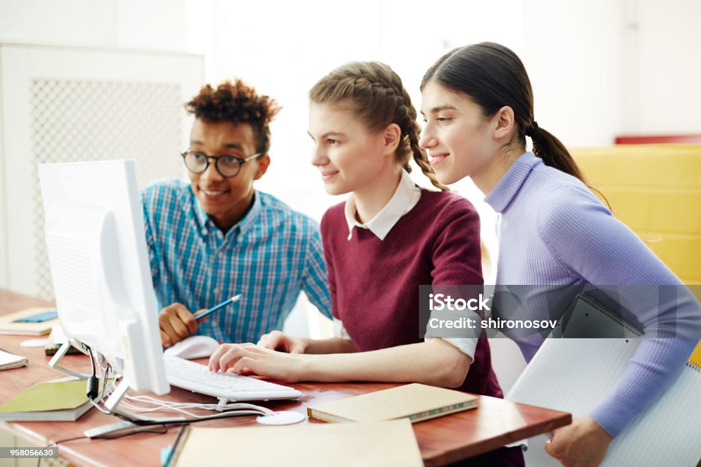 Work of programmers Three young start-upers looking at computer monitor while watching webcast after lessons Learning Stock Photo