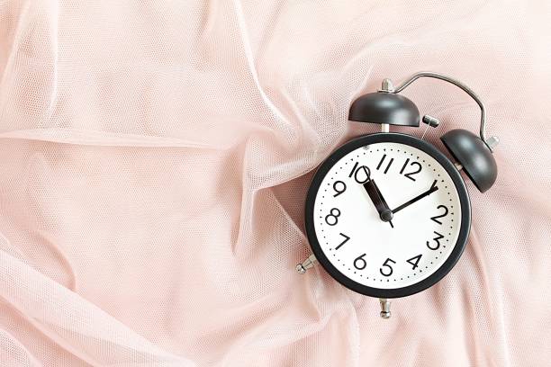 istock Black retro alarm clock on bed in morning, top view or flat lay with copy space ready for adding or mock up 958070360