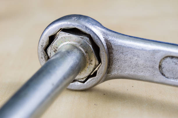 Metric screw and key on a wooden table. Mechanical accessories in the locksmith workshop. Light background.