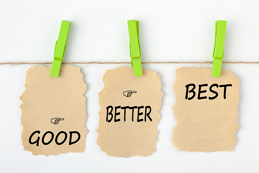 GOOD BETTER BEST writen on old torn paper with clip hanging on white background. Business concept words.