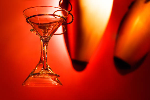 Two martini glasses hanging with a strong red color background.