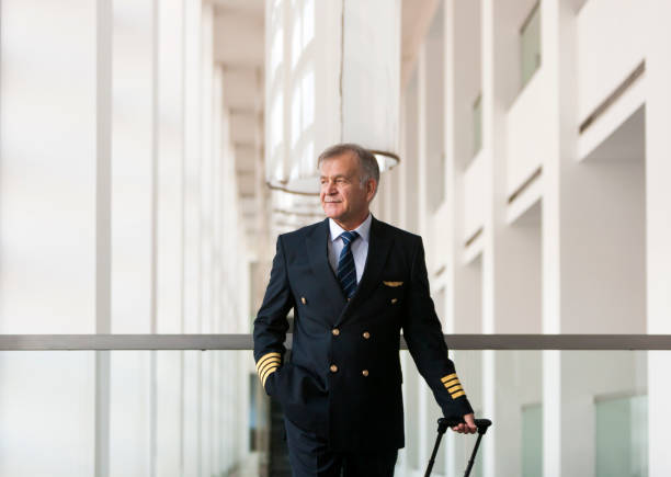 istock Experienced Senior pilot pulling his luggage in the airport terminal 958081896