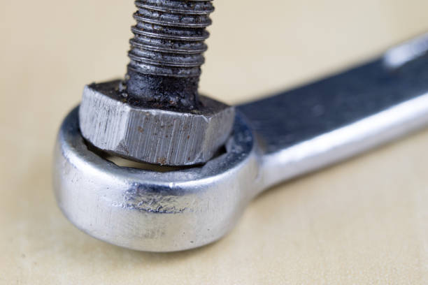 Metric screw and key on a wooden table. Mechanical accessories in the locksmith workshop. Light background.