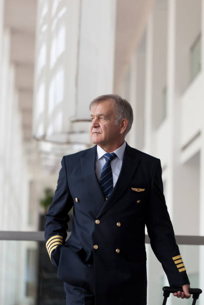 istock Experienced Senior pilot pulling his luggage in the airport terminal 958082032