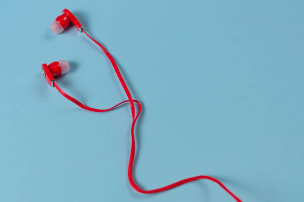 istock Red new earphone with cable on blue paper background with copy space 958086334