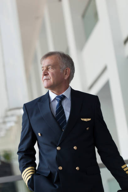 istock Experienced Senior pilot pulling his luggage in the airport terminal 958090186