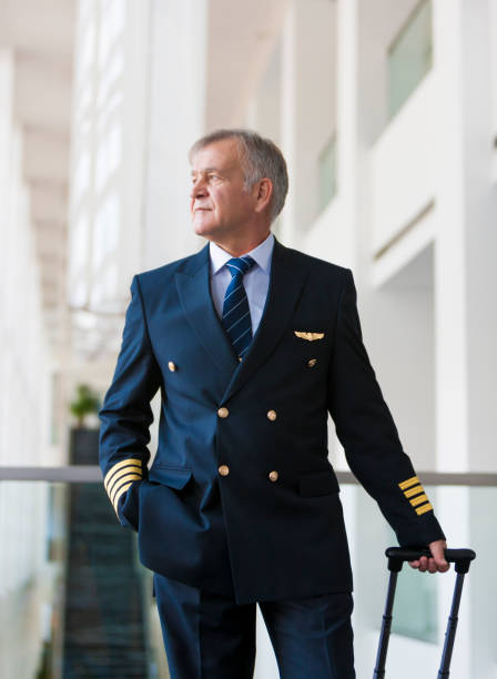istock Experienced Senior pilot pulling his luggage in the airport terminal 958090266