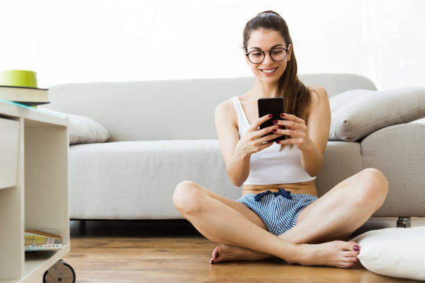 istock Beautiful young woman using her mobile phone at home. 958090618