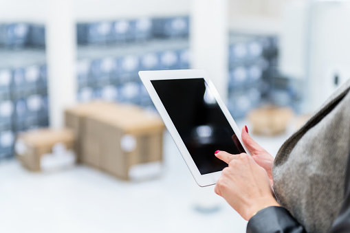 Horizontal color image of warehouse manager standing in warehouse and using digital tablet.